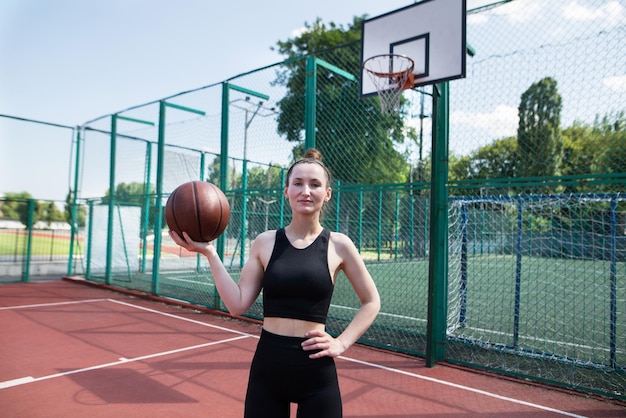 Young sports girl with a basketball on the basketball court outdoors active weekend