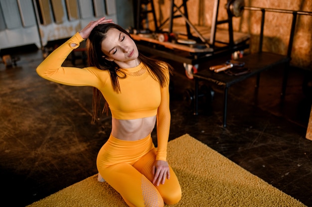노란색 스포츠 유니폼에 젊은 스포츠 소녀 운동에 대 한 준비. 현대적인 로프트 스타일의 체육관.
