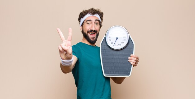 Young sports man holding a weight skale against flat wall