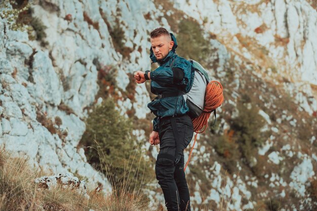 Young sports man looking at heart rate monitor watch outdoor\
young hiker trail hike on the mountain