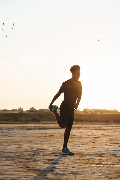 Young sports man makes fitness exercises outdoors