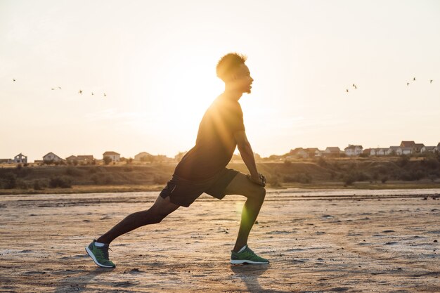 Young sports man makes fitness exercises outdoors