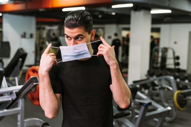 A young sports man puts on a protective mask in the gym