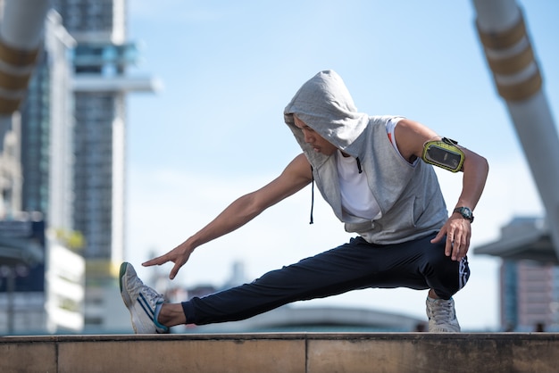 Young sports man stretching legs on the modern city. 