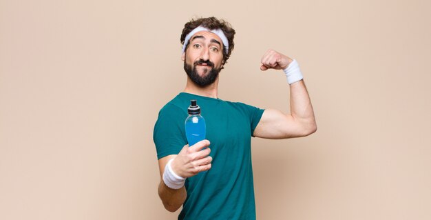 Young sports man with an energy drink bottle against flat wall