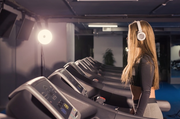 若いスポーツの女性はジムで運動しています。トレッドミルで有酸素トレーニングを行う。
