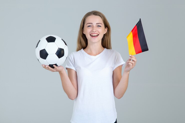 サッカーボールと光のドイツ国旗を持つ若いスポーツ女性