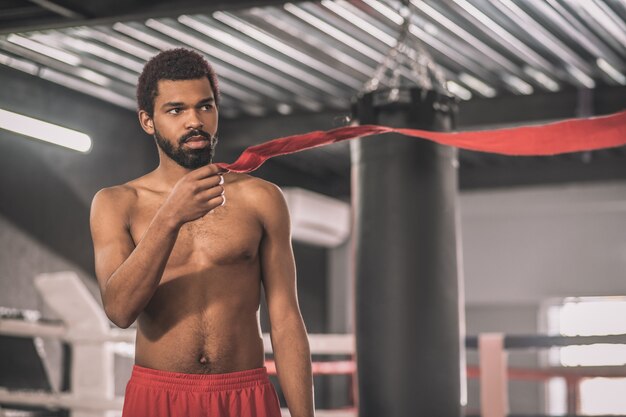 Young sportsman. Dark-skinned young sportsman in a gym getting ready for the workout