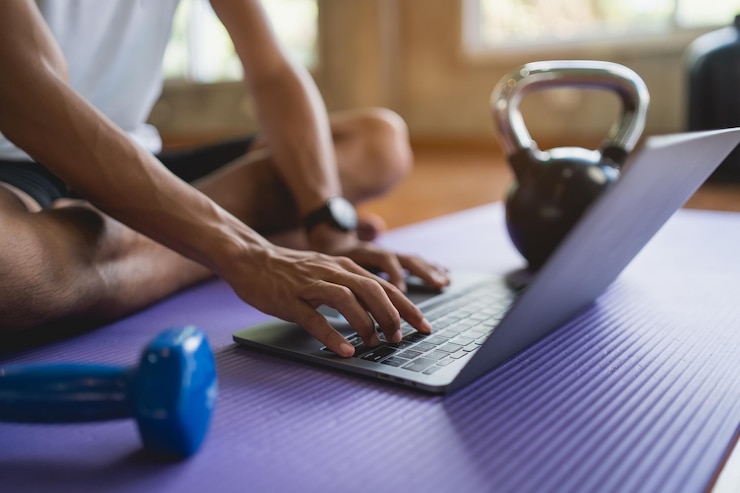 Photo young sportsman sitting on purple yoga mat and doing exercise sports workout online and looking video streaming on laptop indoor at the fitness gym online fitness training from gym concept