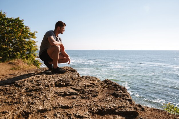 Young sportsman sitting at the seashore