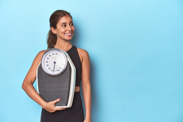 Photo young sportswoman holding a scale in studio