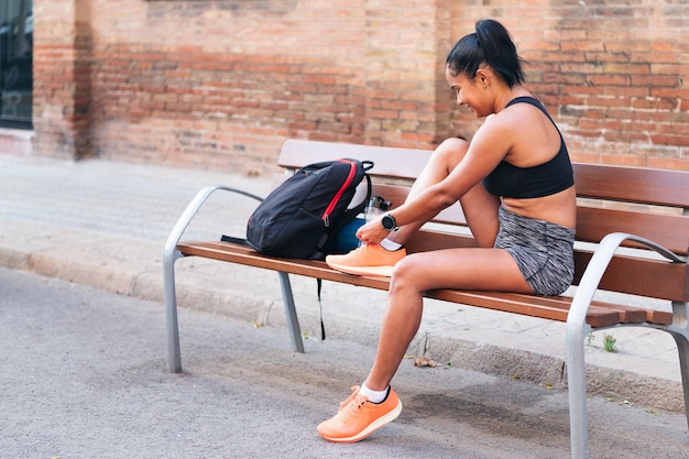 Photo young sportswoman lacing up her running shoes