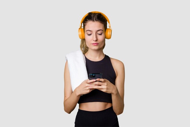 Young sportswoman listening to music motivated and focused holding phone