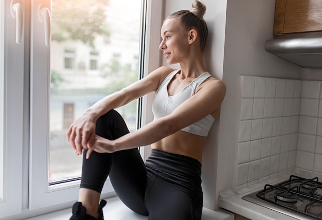 Young sportswoman near kitchen window