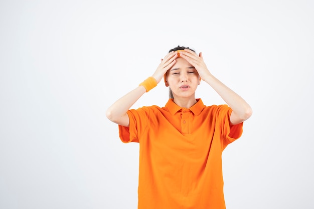 young sportswoman in orange outfit standing and posing.