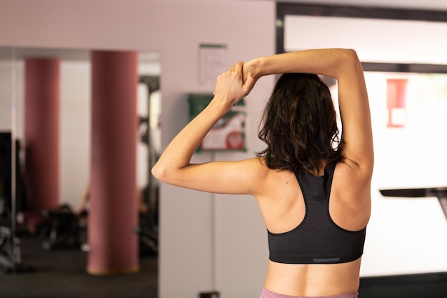 Photo young sportswoman stretching at gym