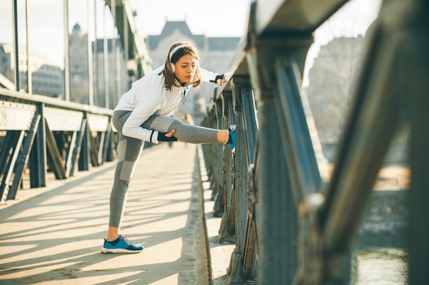 若いスポーツ婦人は伸び、走る準備をしています