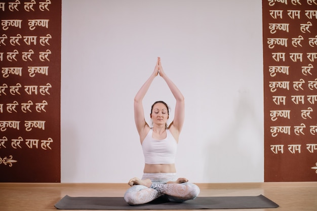 Foto yoga di pratica della giovane donna attraente sportiva, meditando nella posa di yoga