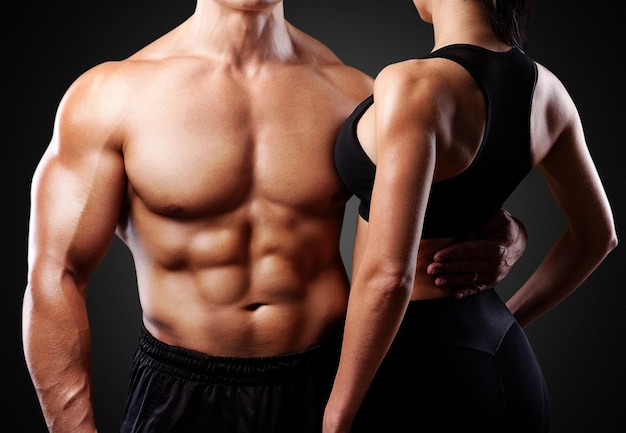 Young sporty couple posing on black background. Black and white photo