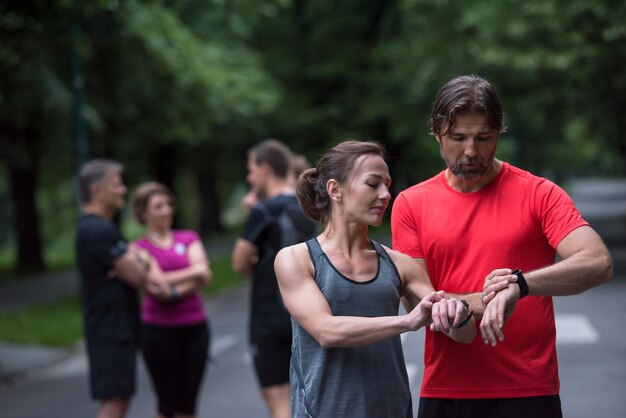 Young sporty couple using smart watches starting their timer before jogging