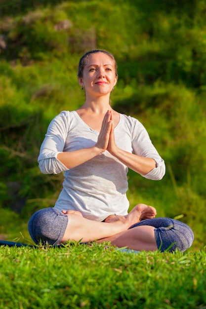 Young sporty fit woman doing yoga Lotus pose oudoors