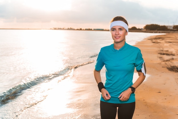 Young sporty girl doing morning exercises on beach at sunrise