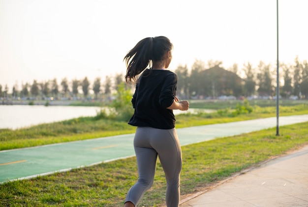 Foto giovane ragazza sportiva che funziona nel parco durante il tramonto