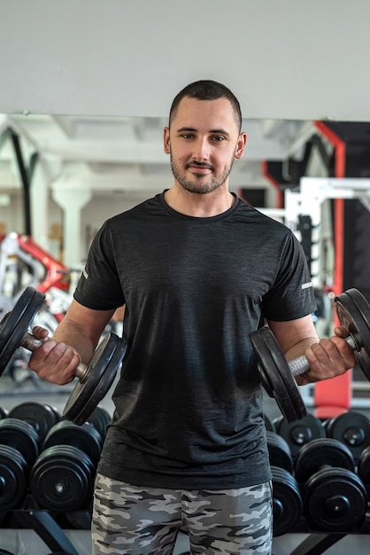 Young sporty man doing exercising with dumbbell in gym weight exercises concept