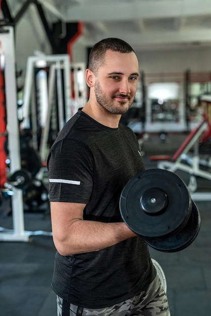 Young sporty man doing exercising with dumbbell in gym weight exercises concept