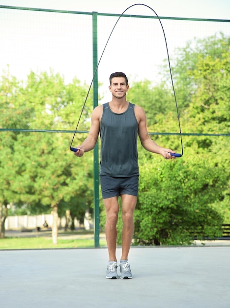 Young sporty man jumping rope outdoors