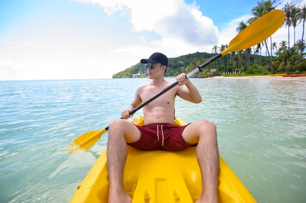 A young sporty man kayaking at the ocean in a sunny day