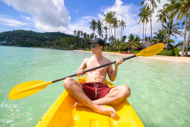 Un giovane uomo sportivo che va in kayak all'oceano in una giornata di sole