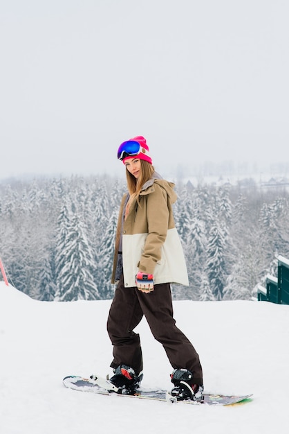 Young sporty smiling woman in winter with snowboard, glasses