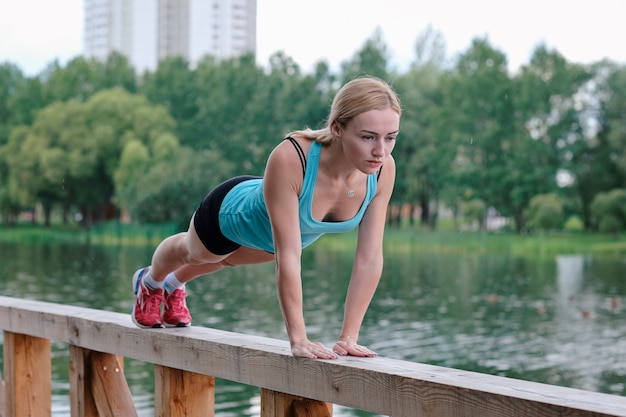 Photo young sporty woman doing sports outdoors, fitness exercises.