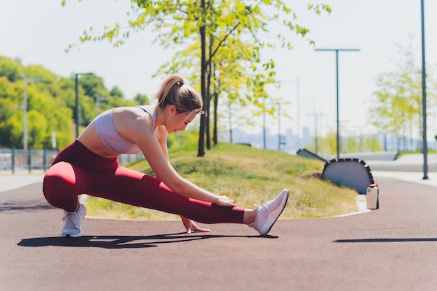 ストレッチ運動の遊歩道をやっている若いスポーティな女性。