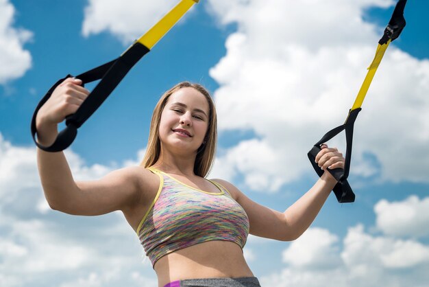 Young sporty woman doing TRX exercises