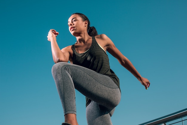 Young sporty woman doing warming up outdoors and putting elbow to the knee