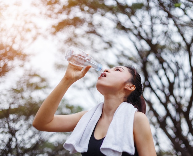 公園で若いスポーティな女性の飲料水