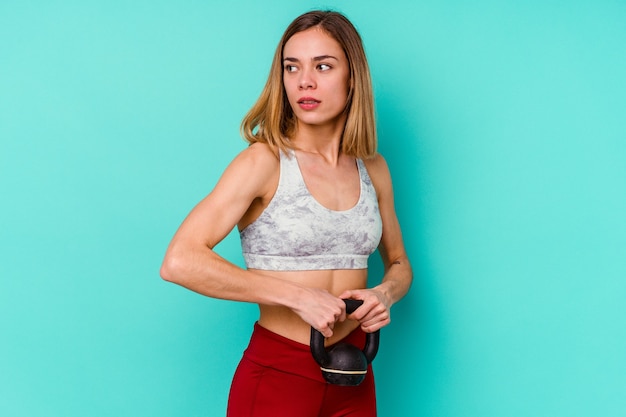 Young sporty woman isolated on blue background