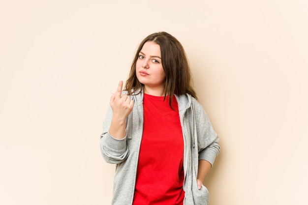 Young sporty woman pointing with finger at you as if inviting come closer.