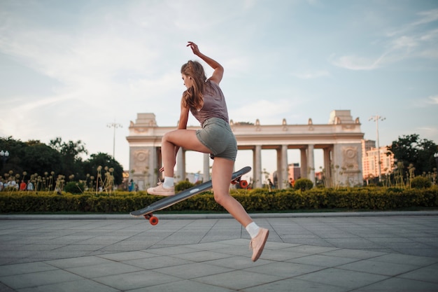 公園のロングボードに乗って若いスポーティな女性