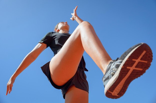 Young sporty woman runner jumping doing lunges training