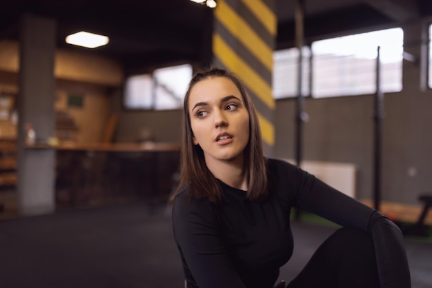 Young sporty woman in sportswear tired and have a break in the gym