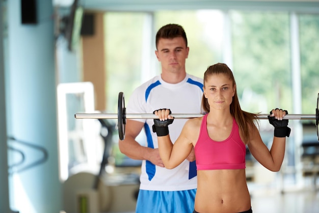 Young sporty woman with trainer exercise weights lifting in\
fitness gym