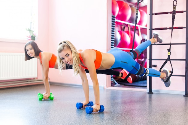 Young sporty women working out at trx loops