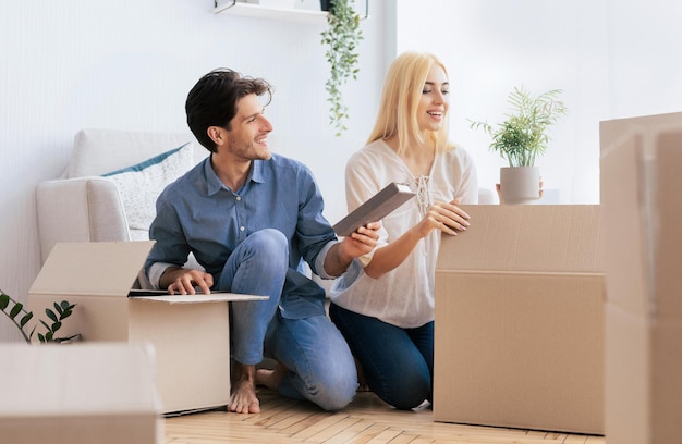 young spouses unpacking moving boxes in new house after relocation