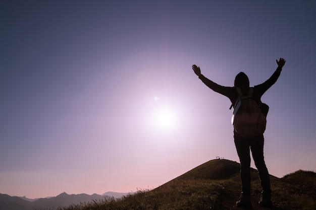 Young standing man with backpack. Hiker on the stone on the seashore at colorful sunset sky. Beautiful landscape with sporty man rocks sea and clouds at sunset. Sporty lifestyle