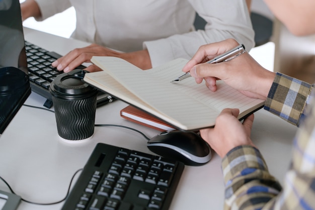 Молодые стартаперы-программисты, сидящие за столами и работающие на компьютере, открывают окно для разработки программ и кодирования, чтобы найти решение проблемы в новом приложении