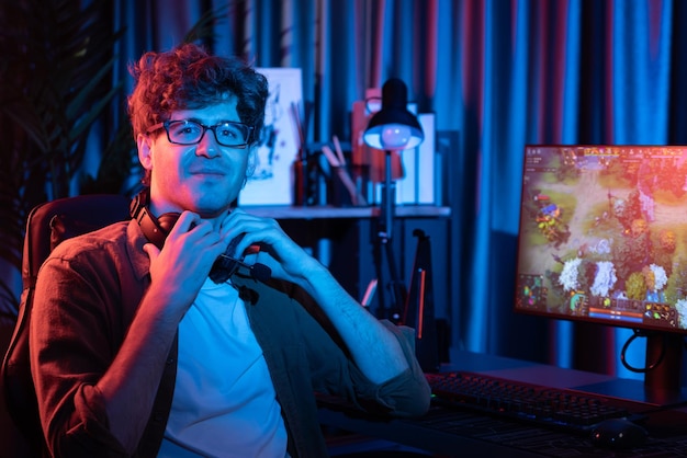 Photo young streamer looking at camera holding headphones in moba screen gusher