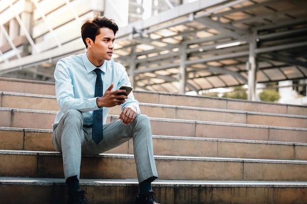 Young Striving Asian Businessman Sitting on Staircase in the City